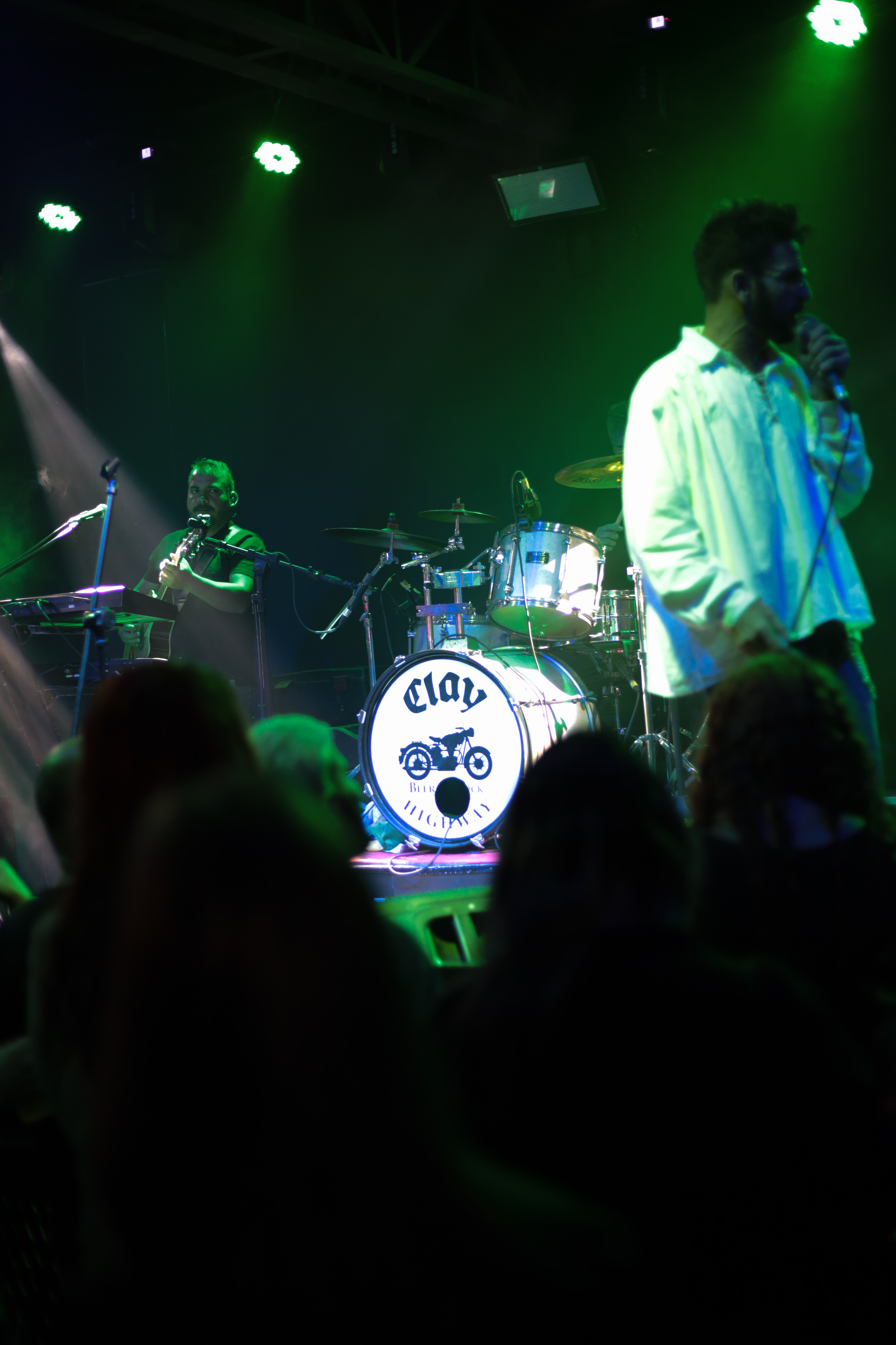 Banda tocando ao vivo no palco do Clay Highway Bar com luzes verdes, Curitiba