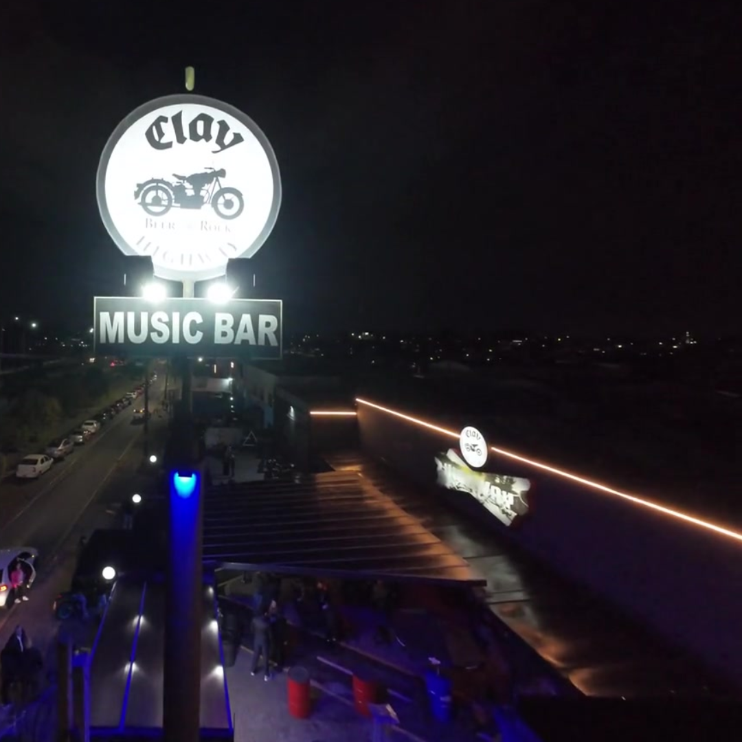Fachada iluminada do Clay Highway Music Bar à noite na Linha Verde, Curitiba